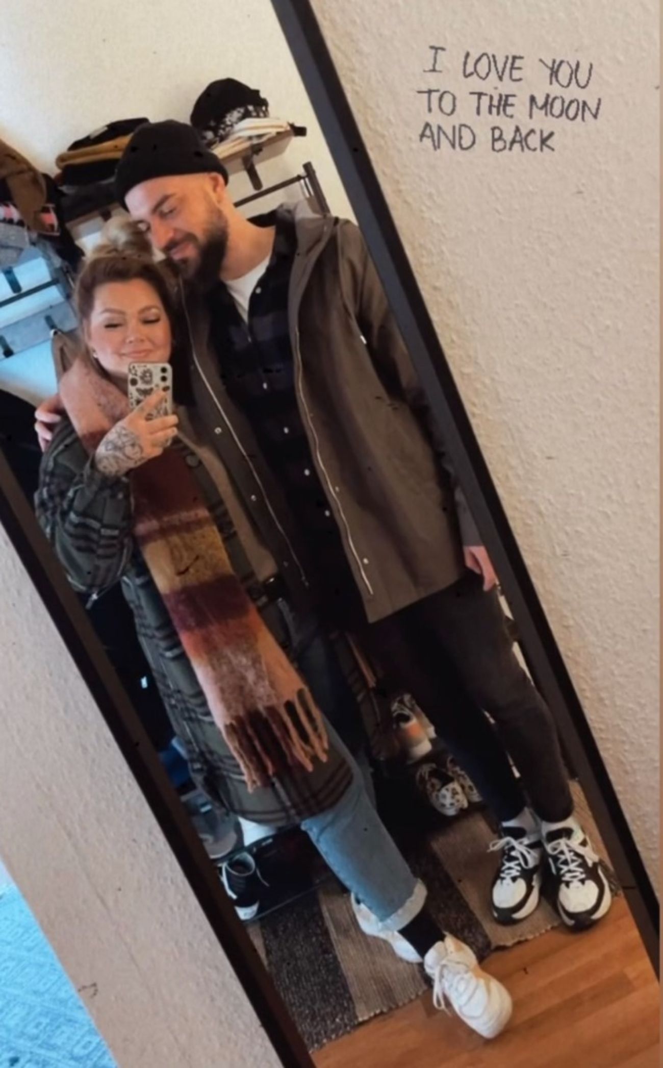 Selfie von Kira und Thomas vor einem Spiegel mit Spruch an der Wand.