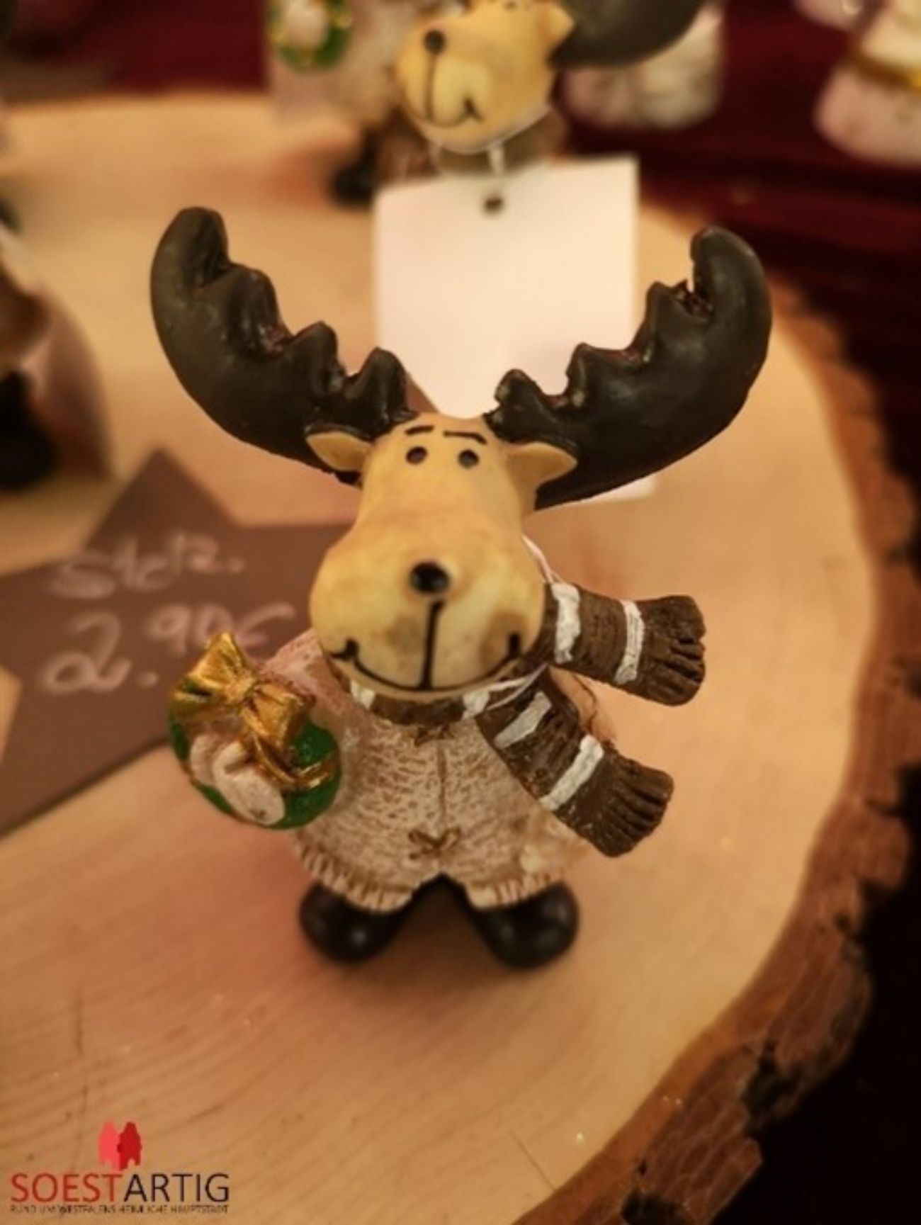 Kleine lächelnde Elchfigur mit Weihnachtskranz