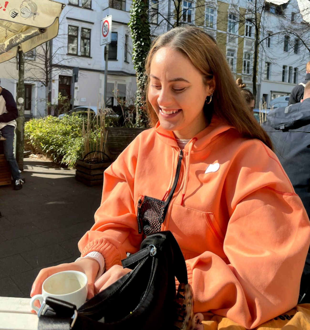 Elena lachend draußen in einem Café.