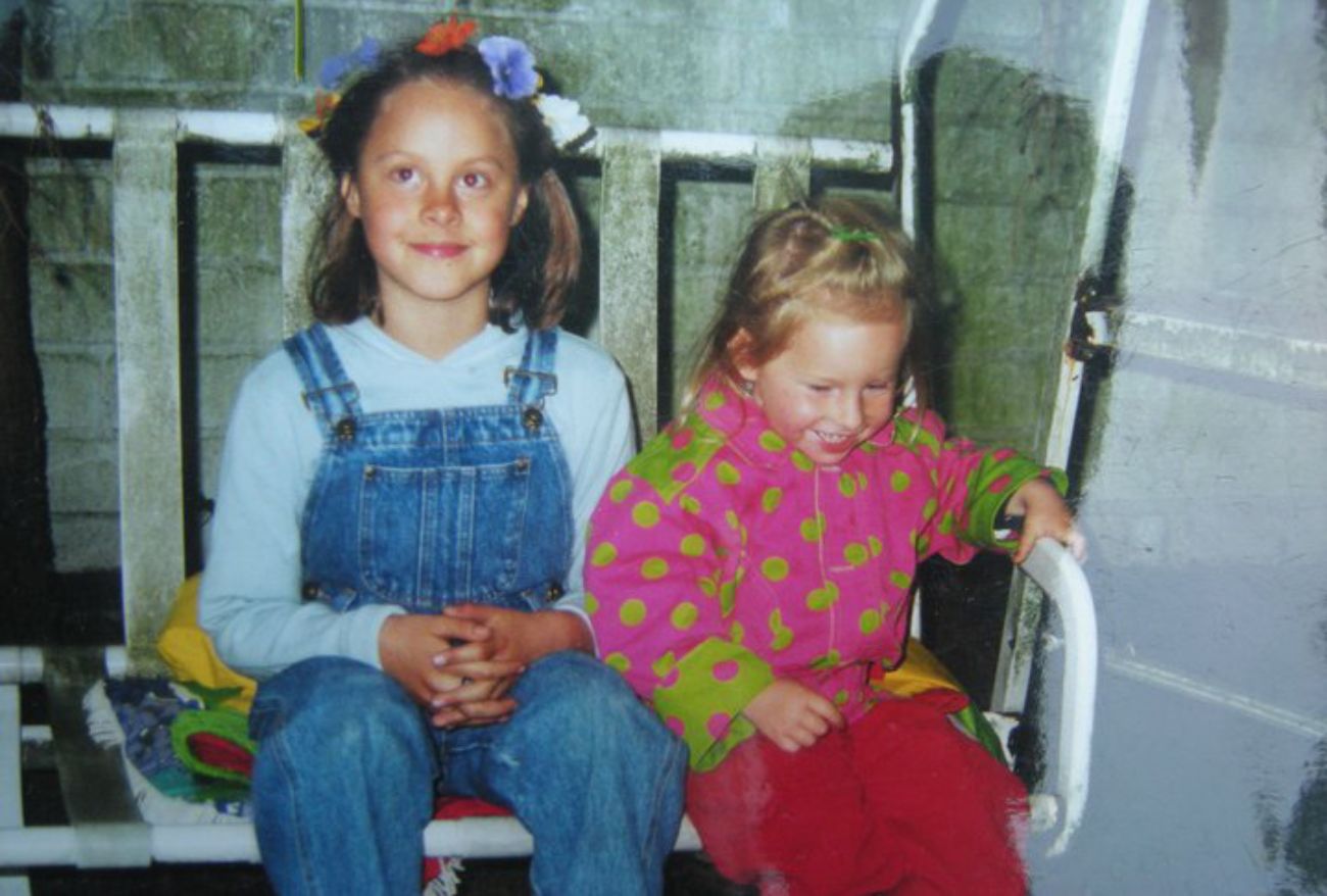 Elena neben ihrer kleinen Schwester sitzend.