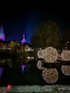 Wasserfläche mit leuchtenden Kugeln und Stadtsilhouette im Hintergrund
