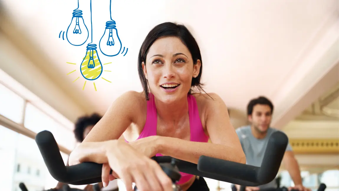 Lachende Frau auf dem Fahrrad im Fitnessstudio