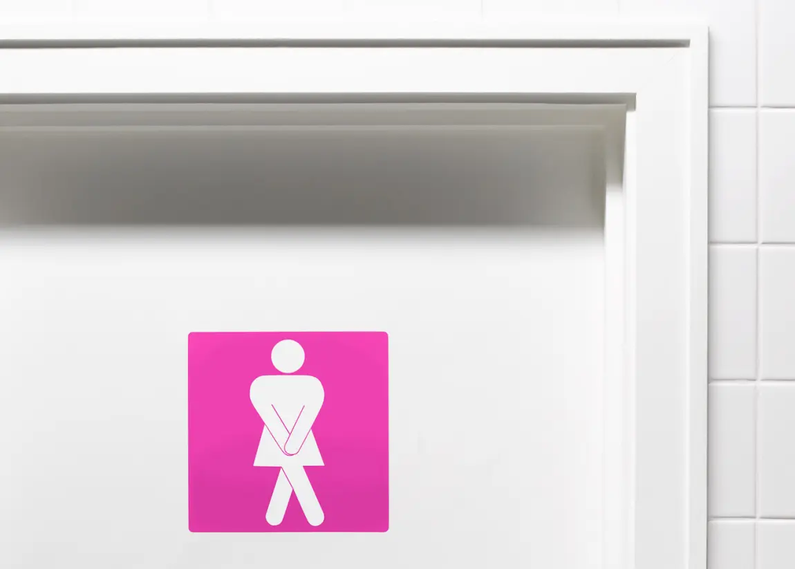 Ein Schild an der Toilettentür zeigt eine verzweifelte Frau, die auf die Toilette muss.